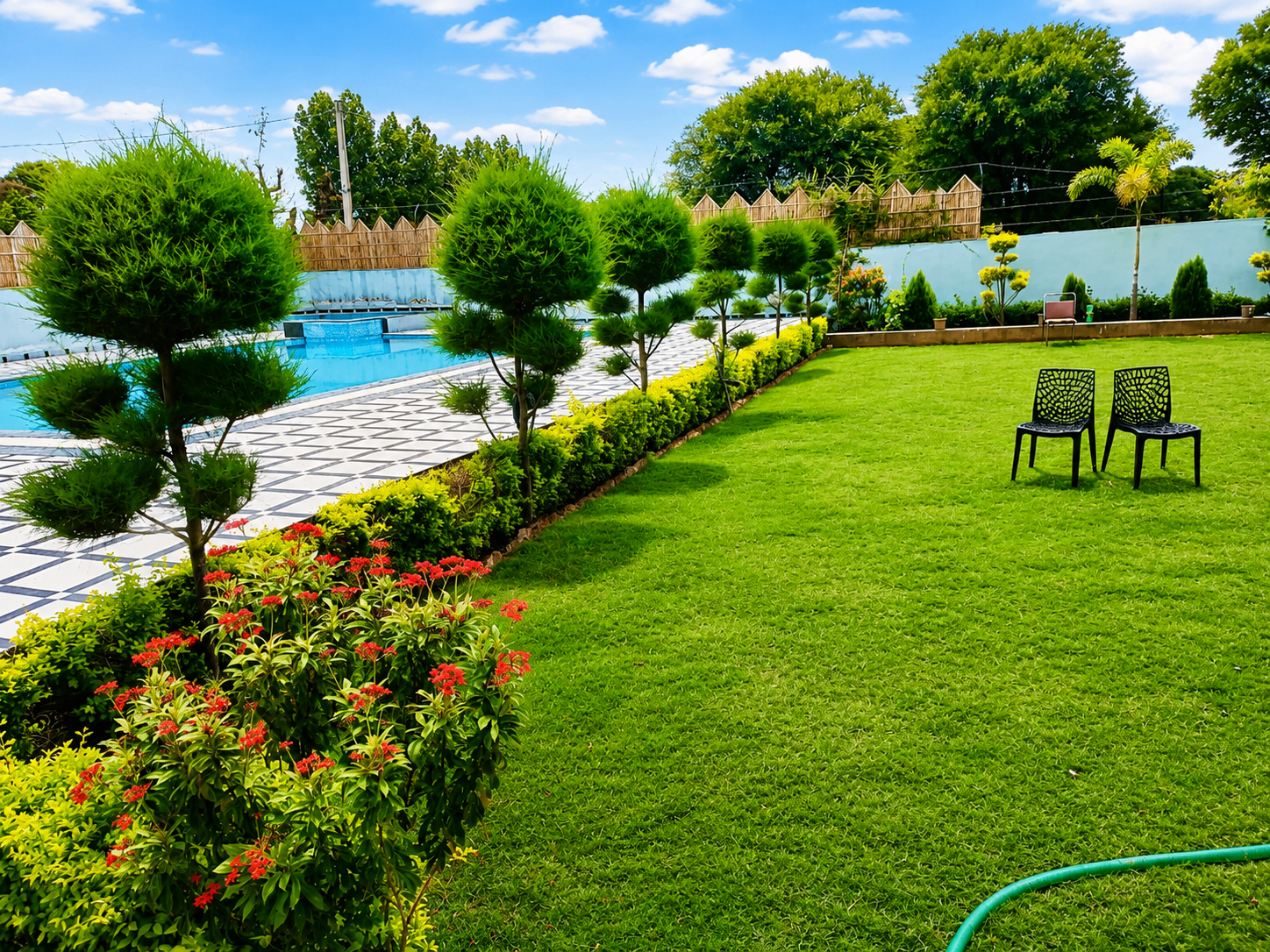 Landscaped lawn with shaped topiary, seating and the swimming pool in the background at Mandiya Villa.