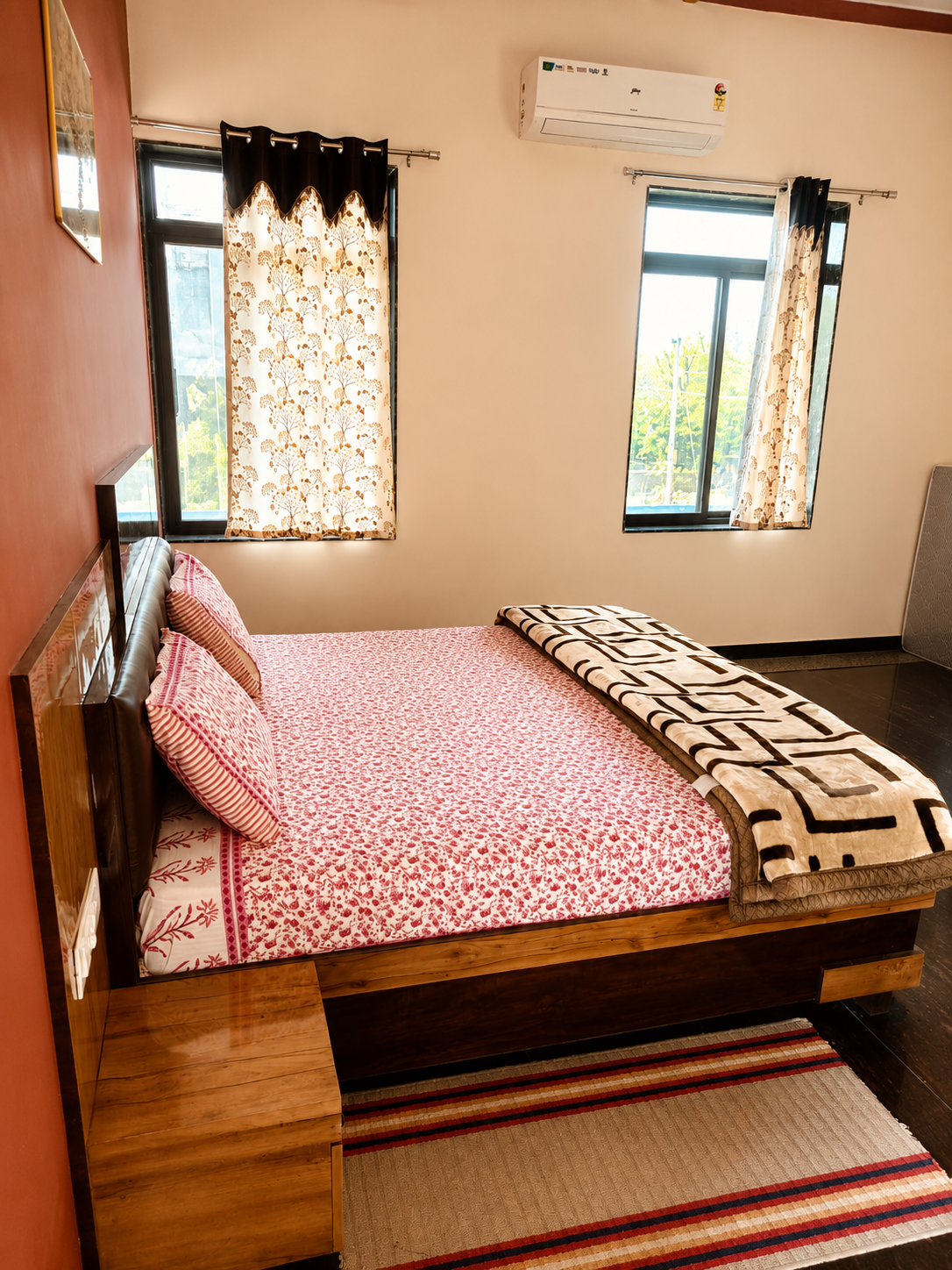 AC bedroom at Mandiya Villa with a double bed, patterned bedding and two large windows letting in daylight.
